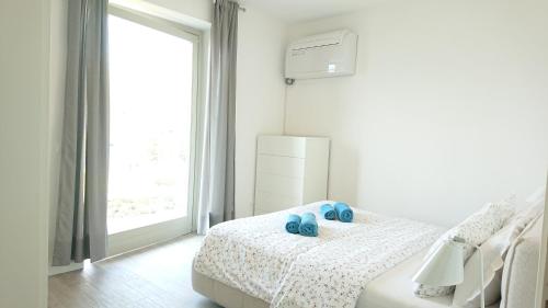 a white bedroom with a bed with blue shoes on it at Lakecomoweb Apartments in Perledo