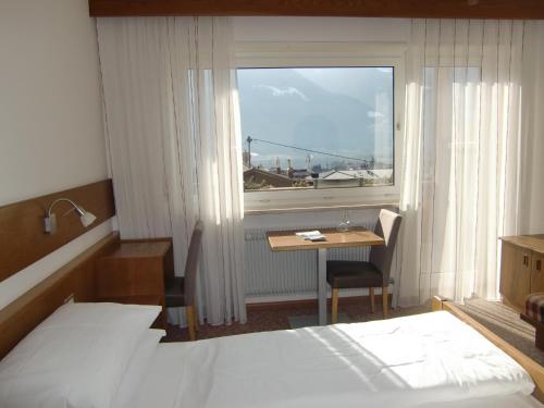 a hotel room with a bed and a table and a window at Pension Lahn in Rablà