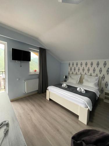 - une chambre avec un grand lit et une télévision dans l'établissement Hotel NOA Kazbegi, à Kazbegi