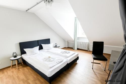 1 Schlafzimmer mit einem großen Bett und 2 Stühlen in der Unterkunft Hotel Blutenburg in München