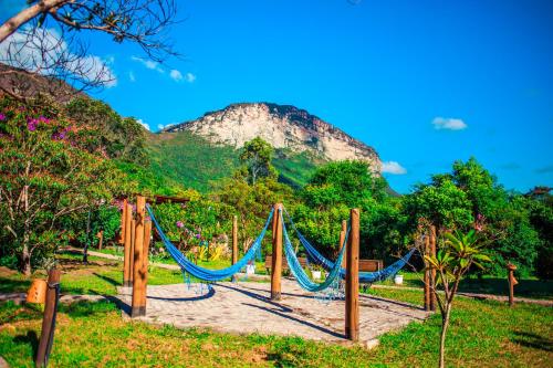 a hammock in a park with a mountain in the background at Pousada Rosa dos Ventos Capão in Vale do Capao