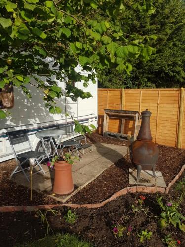 a patio with a table and a vase in a yard at Maes Offa Stays in Llandysilio