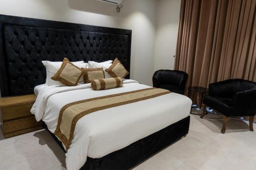 a bedroom with a large bed and two chairs at Trivelles Executive Suites Islamabad in Islamabad