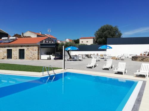 una gran piscina con sillas y sombrillas en Alojamentos Martinho, en Quintas