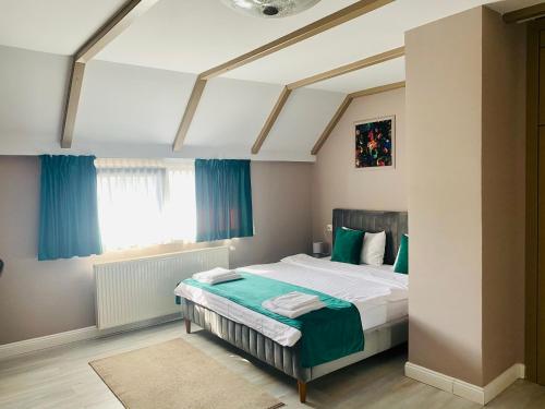 a bedroom with a bed with green sheets and a window at Pensiunea Galileo in Borşa