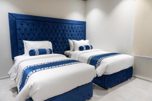 two beds in a room with a blue headboard at Trivelles Executive Suites Islamabad in Islamabad