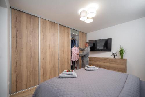 a man is standing in a bedroom with a bed at Apartmány Kaskády Luhačovice in Luhačovice