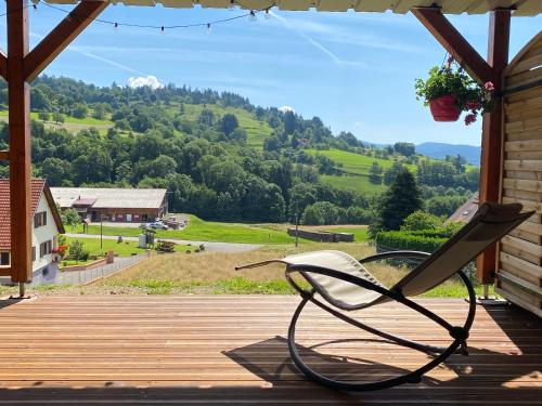 une chaise sur une terrasse couverte offrant une vue sur la montagne dans l'établissement Le chalet de cathy, à Soultzeren