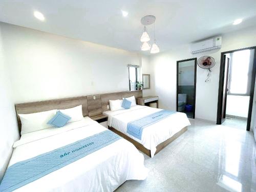 2 bedden in een hotelkamer met witte muren bij Bap Homestay in Hội An