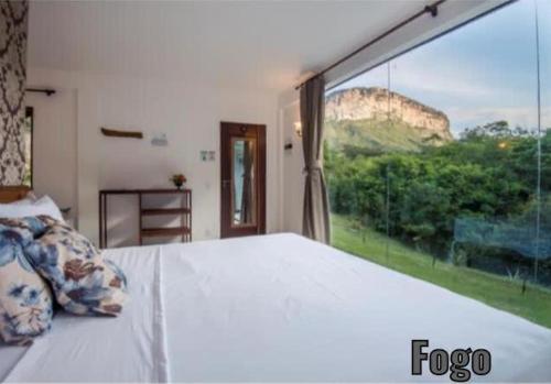 a bedroom with a large bed and a large window at Pousada Rosa dos Ventos Capão in Vale do Capao