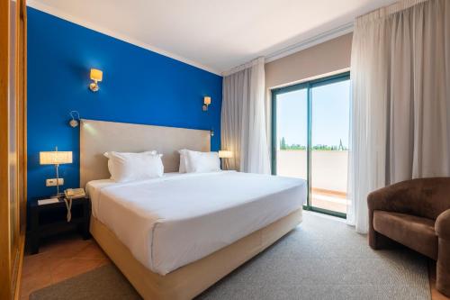 um quarto com uma cama grande e uma parede azul em Vale d'El Rei Hotel & Villas em Carvoeiro