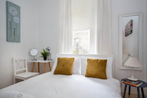 a white bed with two gold pillows in a bedroom at Stockbridge Two Bedroom Apartment in Edinburgh
