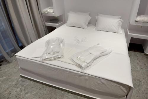 Una cama blanca con sábanas blancas y utensilios. en Rose n Stone, Duke, Luxury Houses en Tinos Town