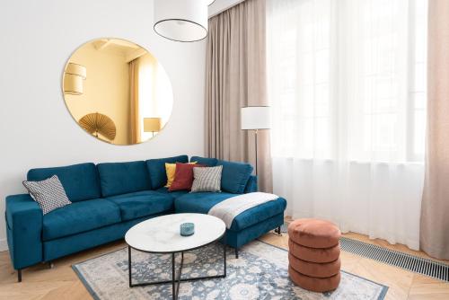 a living room with a blue couch and a round mirror at Warsaw Premium Apartment President Palace in Warsaw