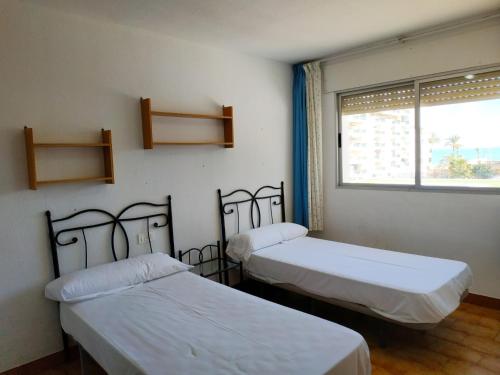 two beds in a room with a window at Peñiscola Playa Orangecosta in Peniscola