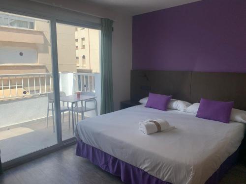 a bedroom with a bed with purple walls and a balcony at Hotel TossaMar in Tossa de Mar