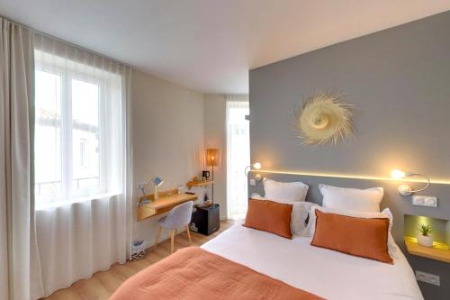 a bedroom with a bed and a desk and a window at Hôtel Le C - Boutique Hôtel in Narbonne