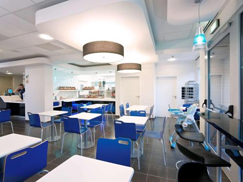 une salle à manger avec des tables et des chaises bleues dans l'établissement ibis budget Torun, à Toruń