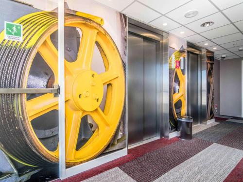a wall with a large yellow wheel on the wall at ibis Calama in Calama