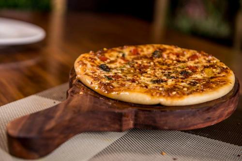 a pizza sitting on top of a wooden cutting board at Club Central in Bolpur
