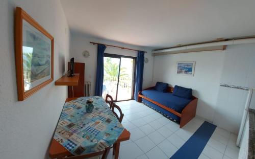 ein Wohnzimmer mit einem Tisch und einem blauen Sofa in der Unterkunft Apartamento Zodiac AB 2 C in Lloret de Mar