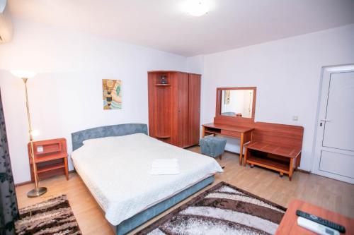 a bedroom with a bed and a desk and a mirror at Family Hotel Ambrozia in Sandanski