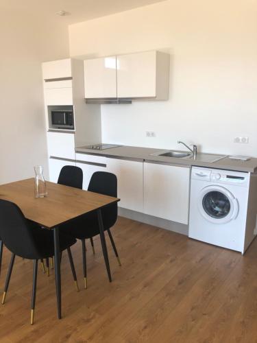 une cuisine avec une table et une machine à laver dans l'établissement Ajaccio appartement 4 couchages, climatisé a 150m de la plage route des sanguinaires, parking privé, à Ajaccio
