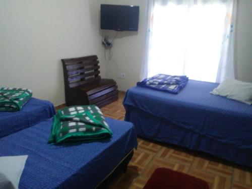 a room with two beds and a tv on the wall at FLAT COM AREA GOURMET para ATÉ 8 PESSOAS in Aparecida