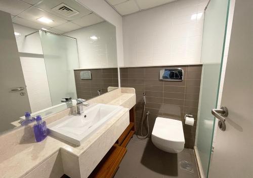 a bathroom with a sink and a toilet and a mirror at Fabulous 1 Bedroom Private Apartment - Waterfront Property in Ras al Khaimah