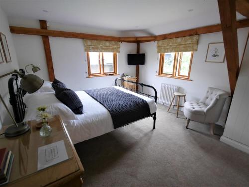 um quarto com uma cama king-size e uma cadeira em North Downs Barn em Rochester