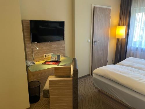 a hotel room with a bed and a desk with a television at Hotel am Untersee in Bantikow