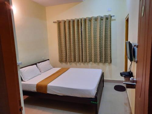 a bedroom with a bed and a window and a television at Royal Suvarna Comforts in Mysore