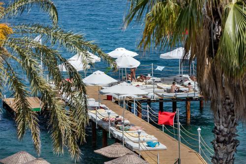 a dock with boats and umbrellas in the water at Grand Ring Hotel in Beldibi