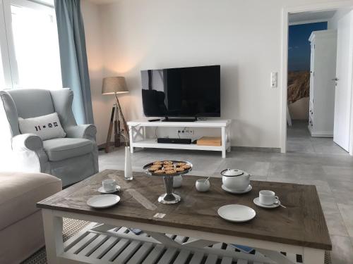 a living room with a coffee table and a tv at OceanView in Wittdün