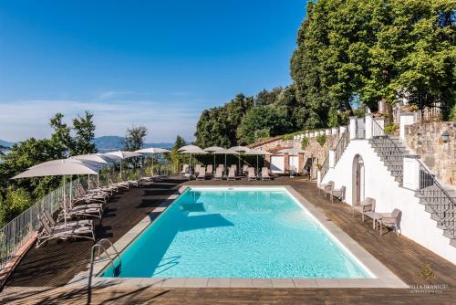 a swimming pool with chairs and umbrellas on a building at Villa Guinigi Dimora di Epoca Exclusive Residence & Pool in Lucca