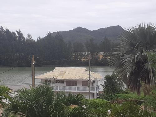 a house on a river with mountains in the background at La Residence D'Almee Guesthouse in Anse Possession