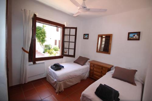 1 dormitorio con 2 camas y ventana en Casa Cristalina Menorca, en Fornells