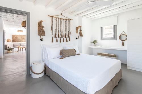 a white bedroom with a bed and a living room at Nesea Sifnos - Luxury Residences in Platis Yialos Sifnos