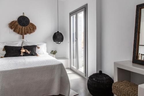 a white bedroom with a bed and a window at Nesea Sifnos - Luxury Residences in Platis Yialos Sifnos