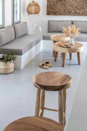 a living room with two tables and a stool at Nesea Sifnos - Luxury Residences in Platis Yialos Sifnos