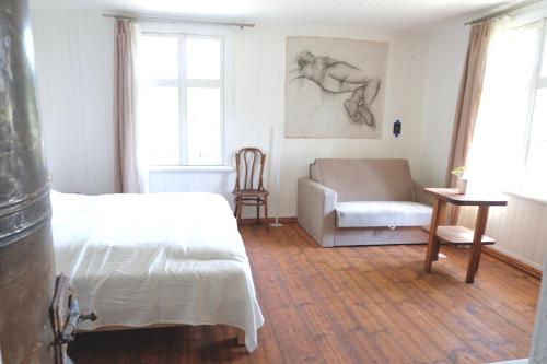 a bedroom with a bed and a chair and a couch at Design apartments Jūrmāja in Ainaži