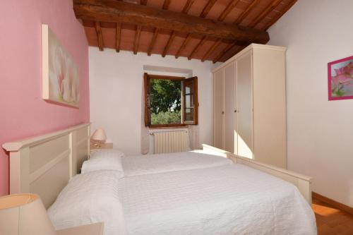1 dormitorio con cama blanca y ventana en Casa Citille, en Greve in Chianti