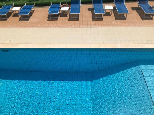 una piscina con sedie a sdraio blu accanto ad essa di Hotel Apogeo a Rimini