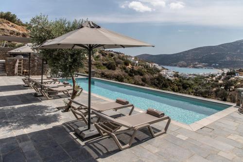 a pool with chaise lounge chairs and an umbrella at Nesea Sifnos - Luxury Residences in Platis Yialos Sifnos