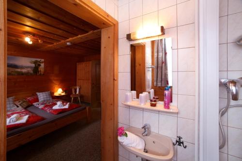 W łazience znajduje się łóżko, umywalka i lustro. w obiekcie Tauernhütte w mieście Piesendorf