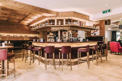 un bar en un restaurante con sillas rojas en Hotel Schwaigerhof en Schladming