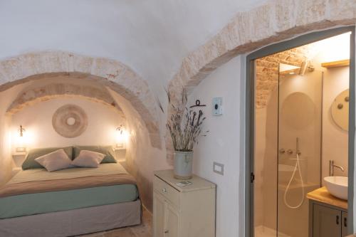 a bedroom with a bed and a bathroom with a sink at Trulli Magheia in Alberobello