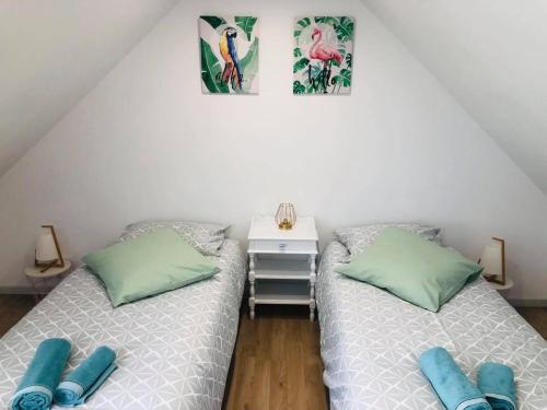 2 Einzelbetten in einem Zimmer mit einem Tisch und 2 Bildern in der Unterkunft Maison de ville, 2ch, La Petite Aure in Bayeux