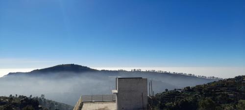 a building on a hill with fog in the valley at B2B Home Stay in Kodaikānāl