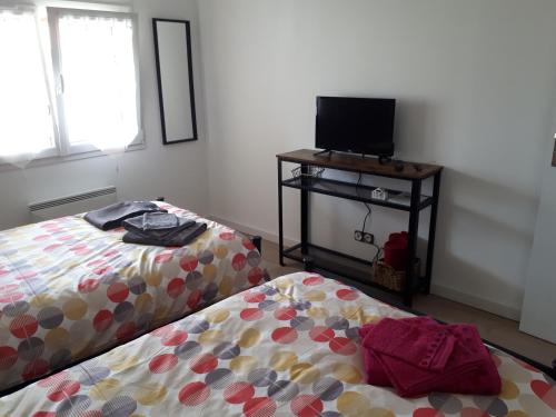a room with two beds and a tv on a table at Gite Amanala Poitou in Saint-Genest-dʼAmbière